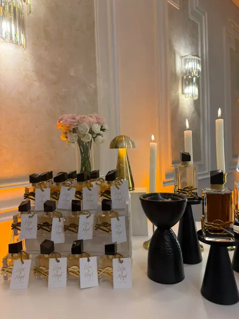 عطور توزيعات مربوط عليها كروت بخط يدوي بأسماء العروسين وتاريخ العرس